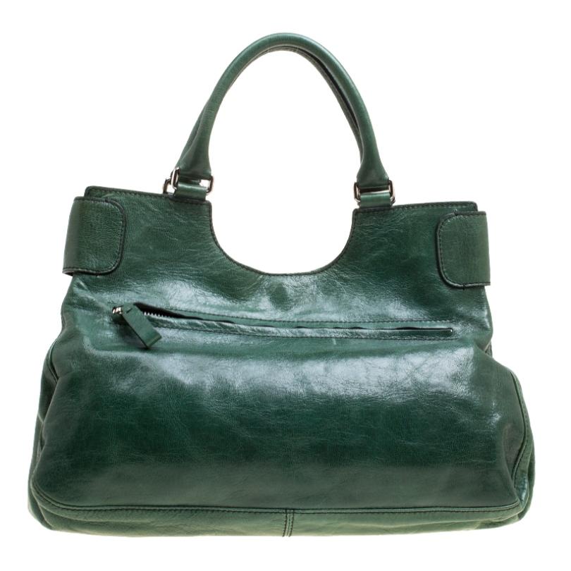 This lush green shoulder bag from Valentino radiates a charm that will amaze the crowds wherever you go! The bag is crafted from leather and features an artistuic silhouette. It flaunts dual top handles, a front flap closure with a crystal
