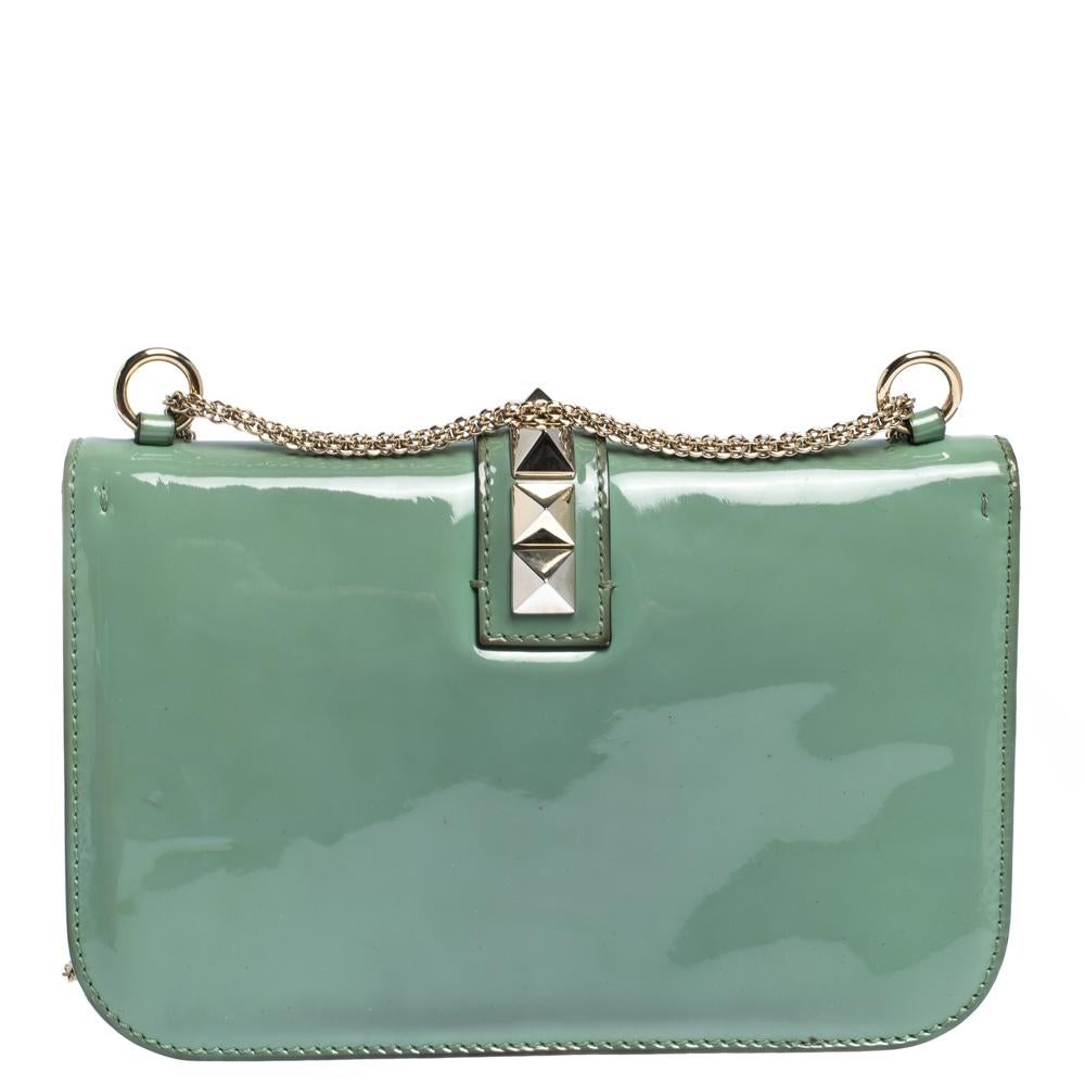 Wenn Sie auf der Suche nach einer Tasche mit einer Mischung aus modernem Stil und Klasse sind:: ist diese Valentino Kreation die Antwort. Das aus Lackleder gefertigte Modell ist mit einer goldfarbenen Kette und einer Klappe ausgestattet:: die das