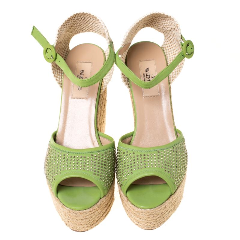 Complete your summer look with these Valentino sandals. Crafted with green leather, the pair features gold studded strap on the front along with buckled ankle straps and lace counters detailed with cutouts. This lovely pair has espadrille wedges