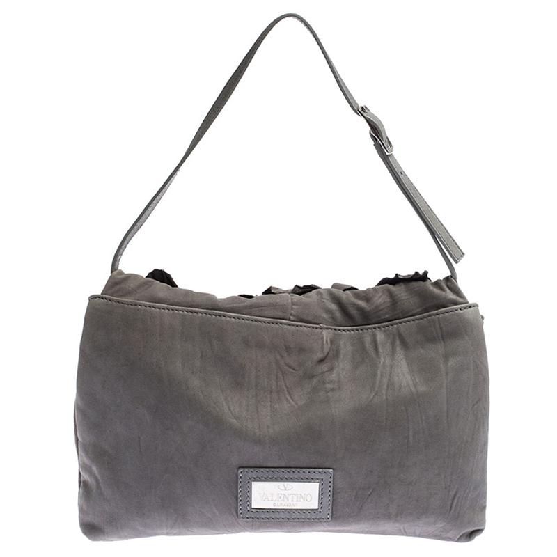 Valentino is known to bring out unique and one of a kind pieces year after year and this bag is indeed one of them! It is crafted from grey leather and features an artistic silhouette. It flaunts a flower applique detailing at the front flap and a