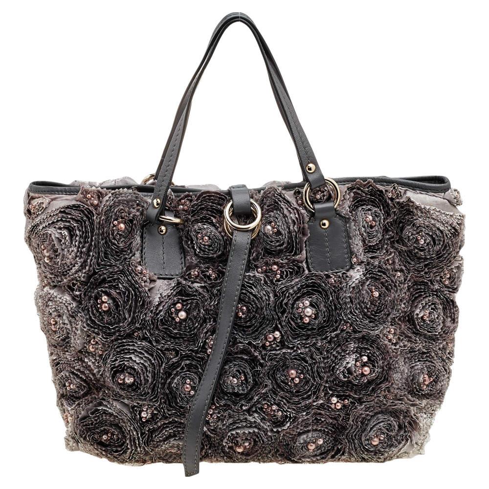 Step out fashionably with this stunning Valentino tote from the beautiful Rosier collection. This unique bag has been crafted using grey silk and leather and is covered in rose appliques and carefully placed pearls. The bag is complete with dual