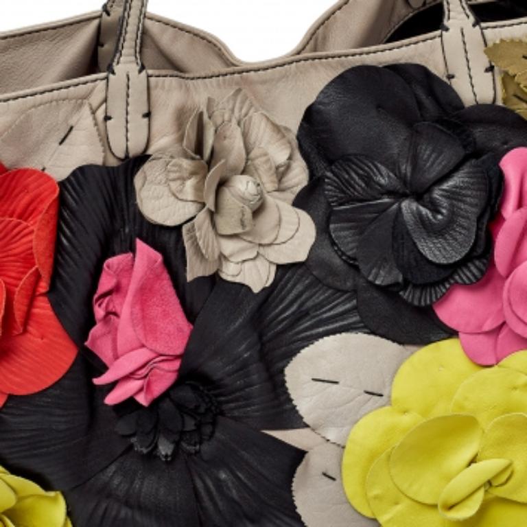 Valentino è noto per proporre ogni anno pezzi unici e irripetibili e questa tote è davvero uno di questi! È realizzata in pelle grigia con applicazioni floreali sul davanti e una targhetta con il marchio sul lato. È dotato di doppi manici e di un