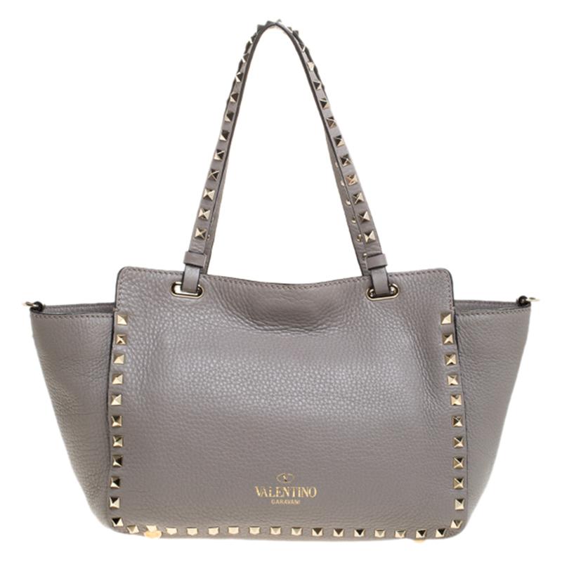 Valentino brings you this super-stylish tote that carries a design which will surely grab the attention of your onlookers. It has a grey leather exterior decorated with the signature pyramid Rockstuds. The tote is complete with a spacious leather