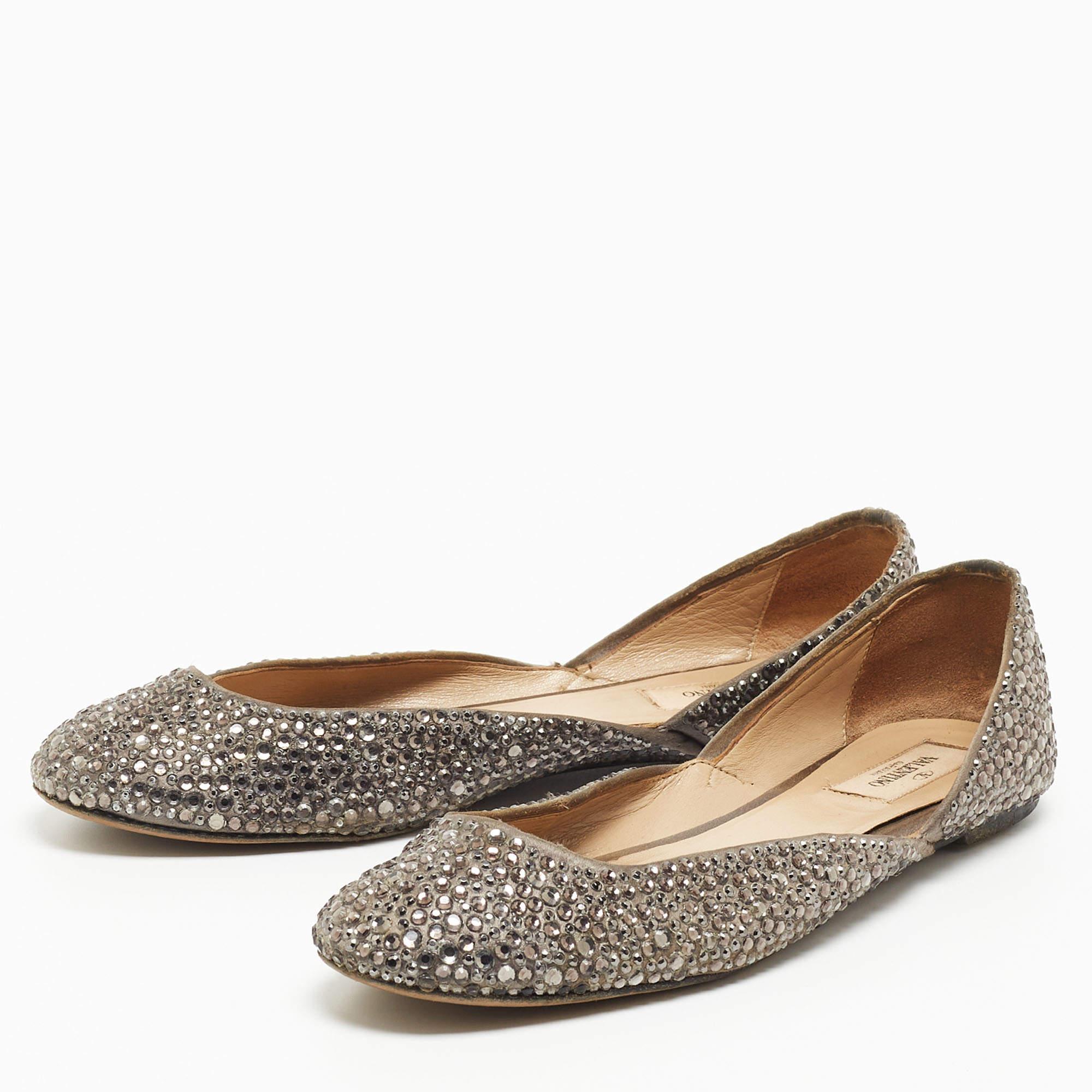 Ces élégantes ballerines proviennent de la maison emblématique Valentino. Fabriqués en satin, ils se déclinent dans une jolie nuance de gris. Elles ont un extérieur embelli et des semelles en cuir. Les acheter maintenant