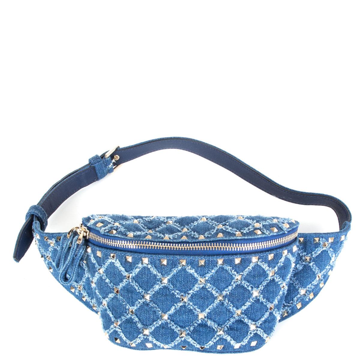 100% authentic Valentino Rockstud denim belt bag in indigo blue quilted cotton with signature light gold-tone pyramid studs. Opens with a double zipper and is lined in blue denim with a red calfskin zipper pocket. Has been carried and is in