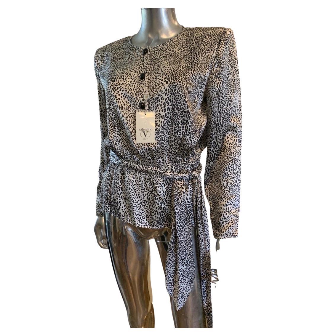 Eine schöne Vintage aber NWT schwarz & weiß Leopard Seide Bluse von Miss V für Valentino. Diese in Italien gefertigte Bluse ist einfach umwerfend. Schwarze Jet-Knöpfe ergänzen ein Schößchen mit integriertem Schal zum Binden in der Taille. Auch ein