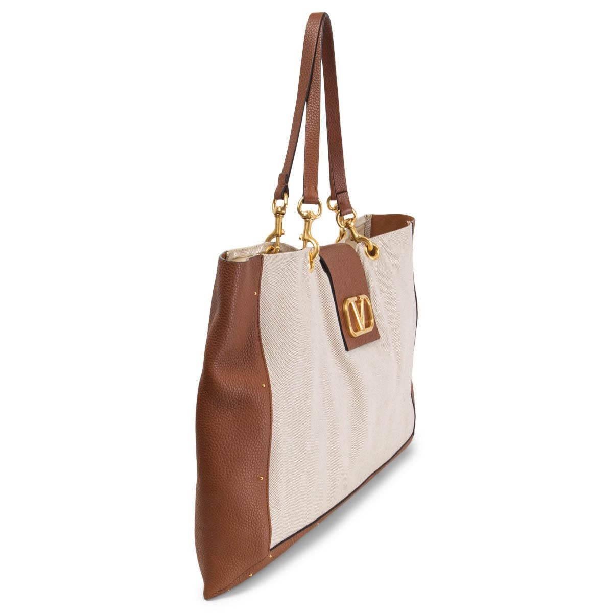 100% authentic Valentino Garavani City Safari tote bag in off-white canvas and cognac grained leather. Features removable handles and micro studs, a magnetic button closure, the iconic VLogo, off-white canvas lining and a red leather contrast zip