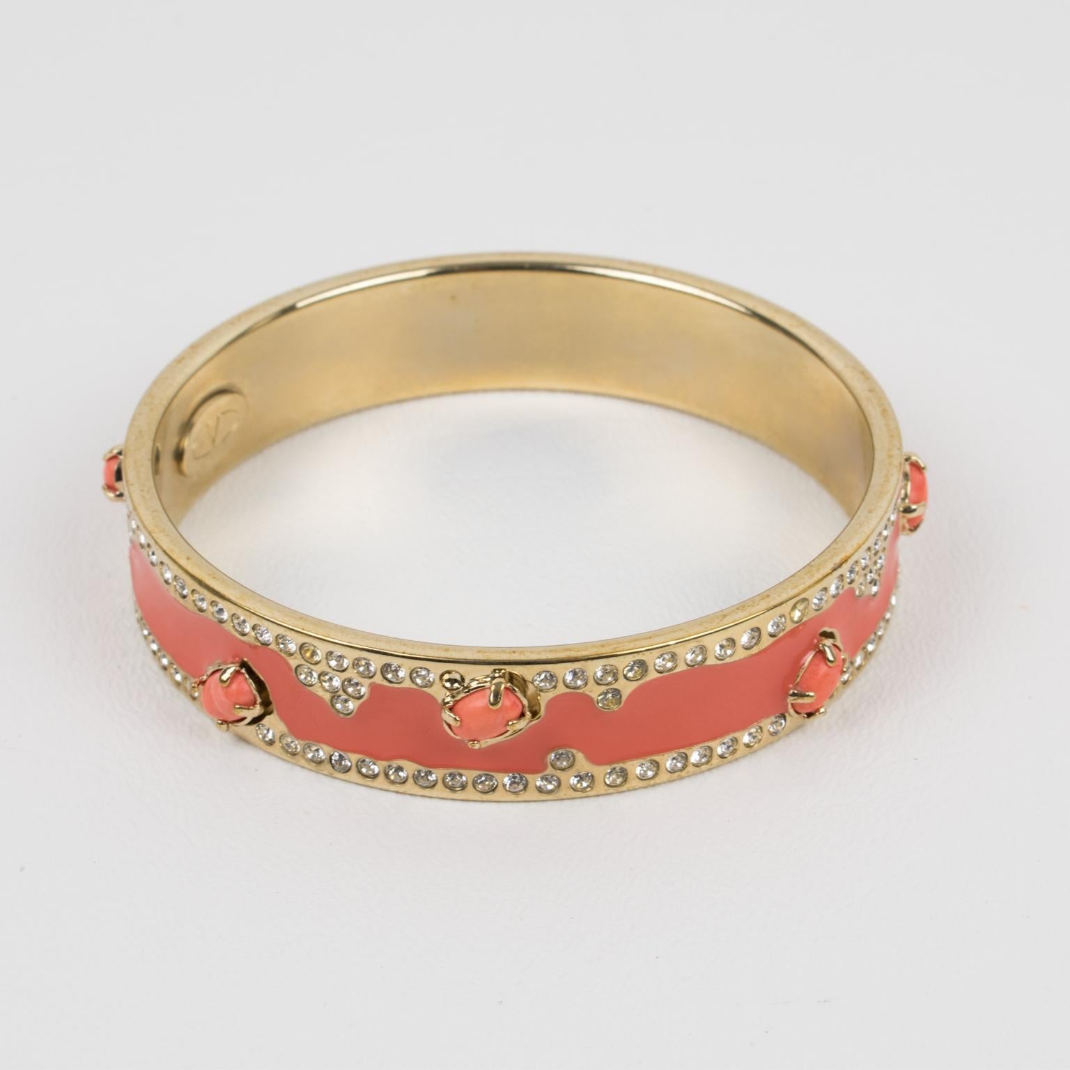Mesmerizing Valentino Garavani jeweled bracelet bangle. Gilt metal bangle shape ornate with tiny crystal rhinestones and pink-coral enamel. The bracelet is also complimented with poured glass pink coral cabochons. Valentino hallmark ovoid brand logo