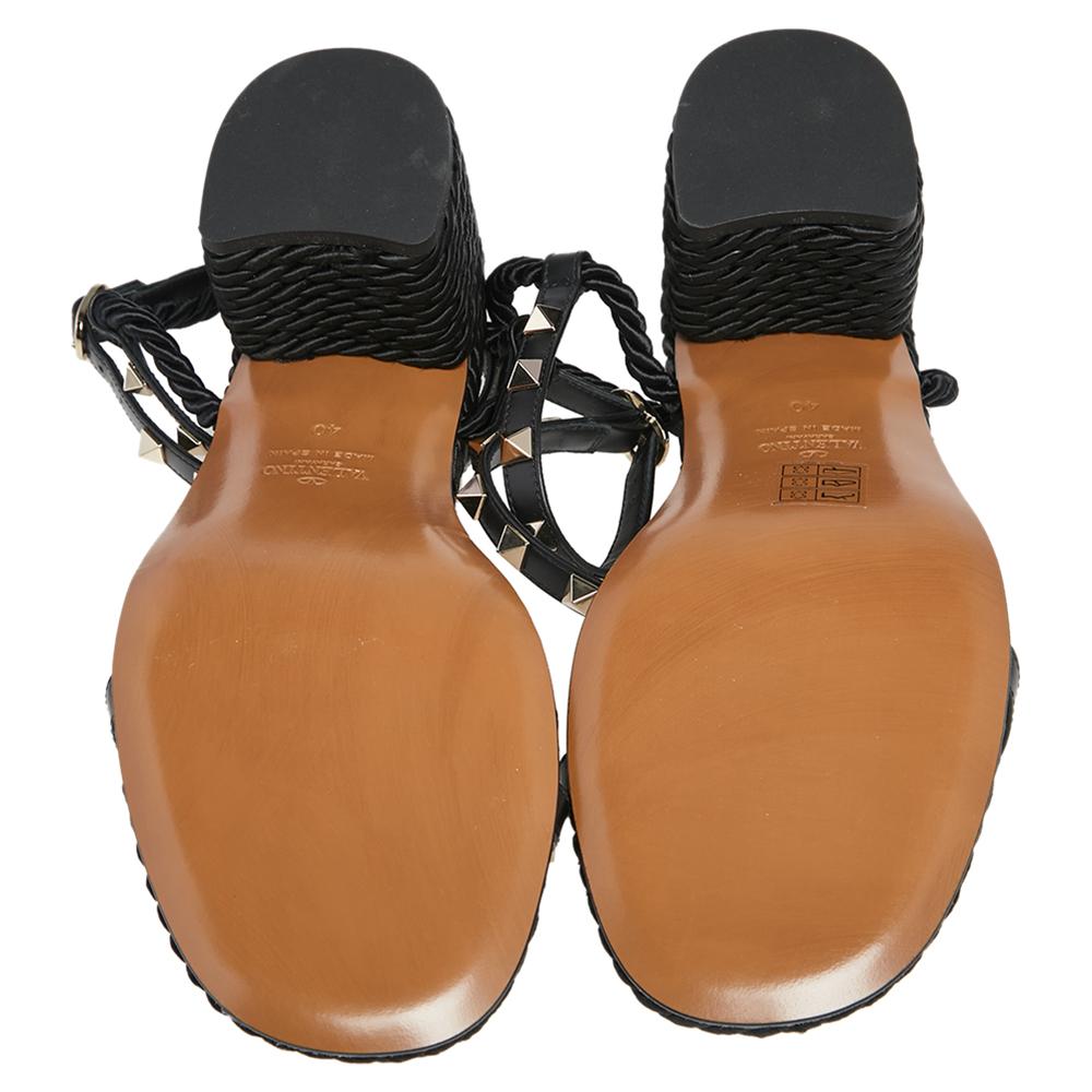 Set on slender heels, these Valentino sandals feature a black leather body accented with rope accents. It comes with Rockstud embellishment on the vamp and ankle straps. Secured with buckle closure, this pair is a must-have in your collection this