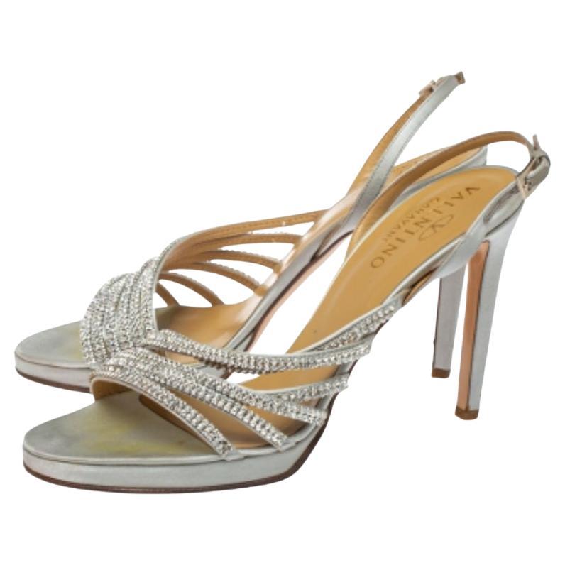 Create the most eye-catching party looks wearing these super stylish Valentino sandals. Constructed from light grey satin, these open-toe sandals along with their slingbacks and 11.5 cm heels, feature exquisite crystal-embellished vamp straps.