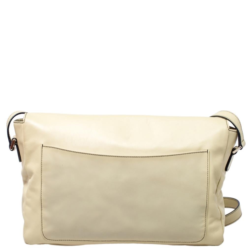 This simple and elegant clutch is from the house of Valentino. Crafted from light yellow leather, it features a front flap with the brand's logo in gold-tone and a patch pocket at the back. The bag comes with an adjustable shoulder strap and a