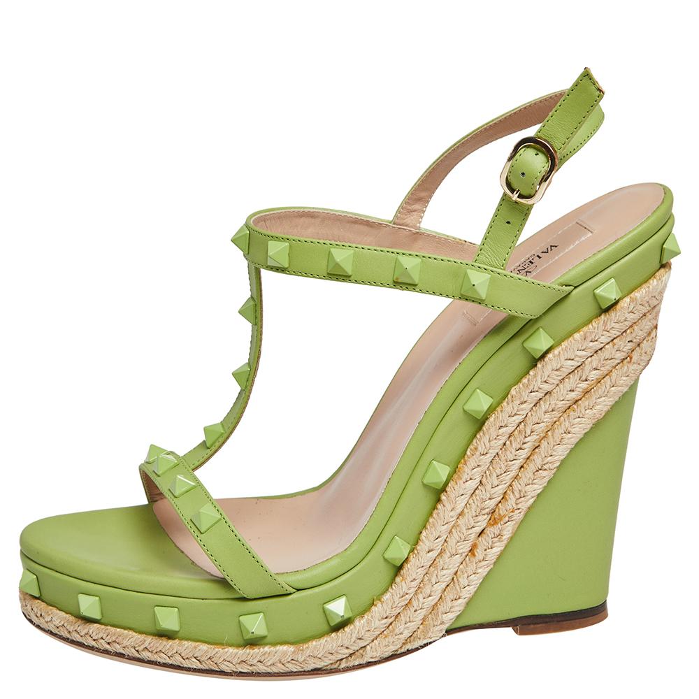 Get full comfort with these Valentino shoes that bring vibrant style. They are designed with open toes, ankle fastenings, and their signature Rockstuds. Elevated on 14 cm espadrille-detailed wedges, this pair will make a worthy buy.

Includes: