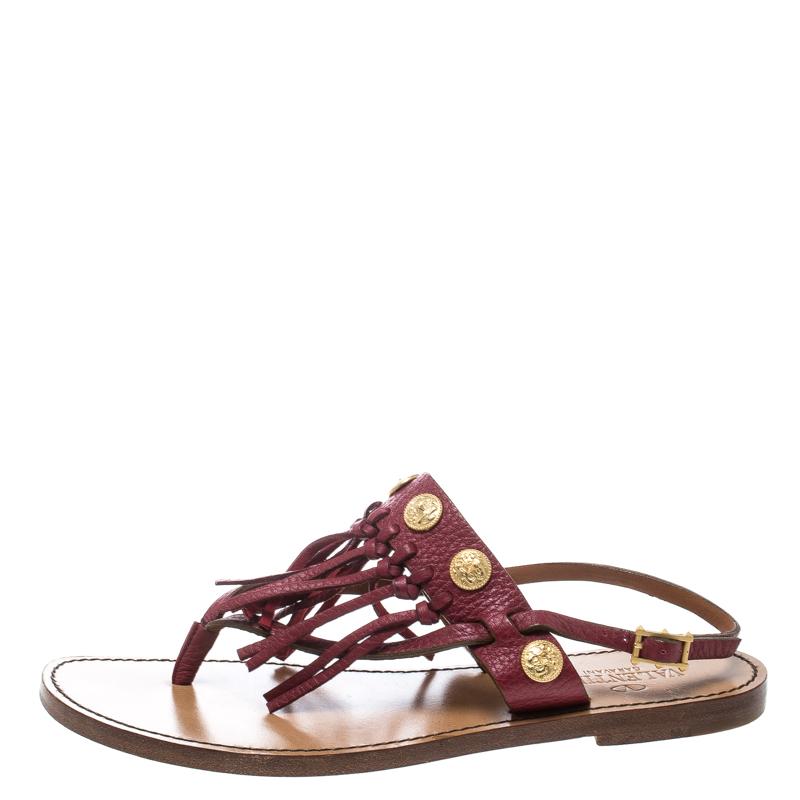Valentino never fails to impress and manages to win our hearts every time! These maroon sandals are crafted from leather and feature an open toe silhouette. They flaunt a thong design with a fringe and gold-tone coin detailed vamp strap that looks