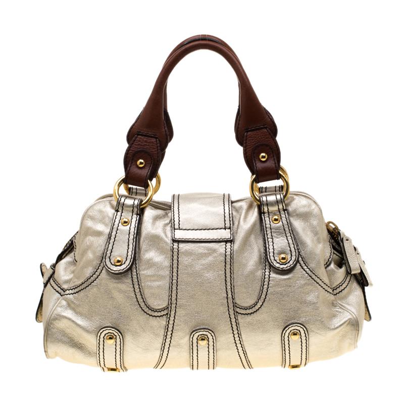 This metallic gold satchel from Valentino radiates a charm that will amaze the crowds wherever you go! The bag is crafted from leather and features an artistic silhouette. It flaunts dual top handles, front flap closure with a crystal embellished