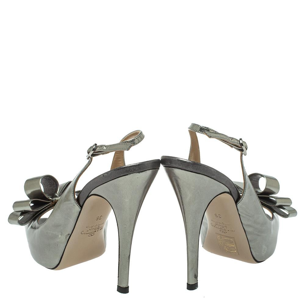 Luxuriously crafted slingback peep-toe pumps by Valentino to offer you an elegant look. They are covered in metallic grey leather, enhanced with bows, lined with leather, and lifted on 11.5 cm slim heels.

