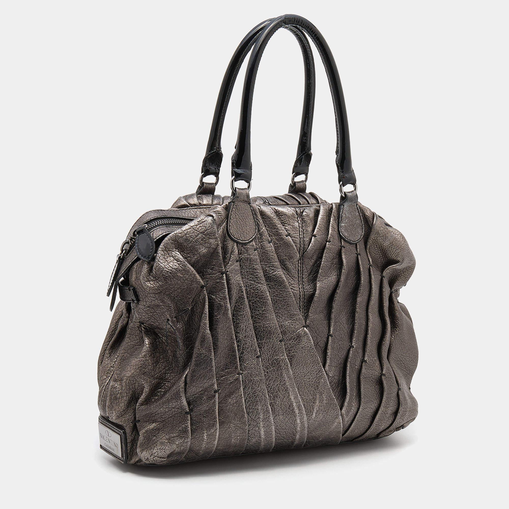 A timeless creation from the house of Valentino, this shopper tote is full of charm. Crafted from metallic grey leather, it features a pintucked exterior and silver-tone hardware. The tote comes with two handles and its well-lined interior will