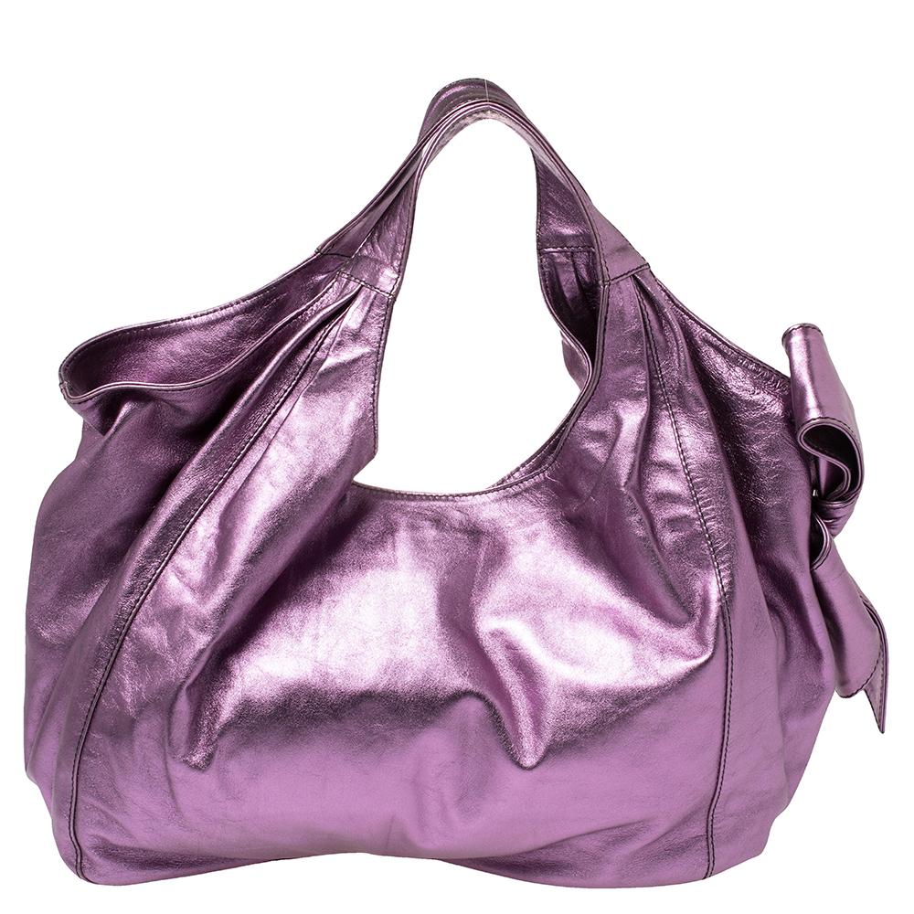 Go for a sophisticated yet girly look with this Nuage tote by Valentino. The bag is crafted from metallic purple leather accented with an over-sized bow and comfortable shoulder straps. Its spacious interior is lined with canvas and features a zip
