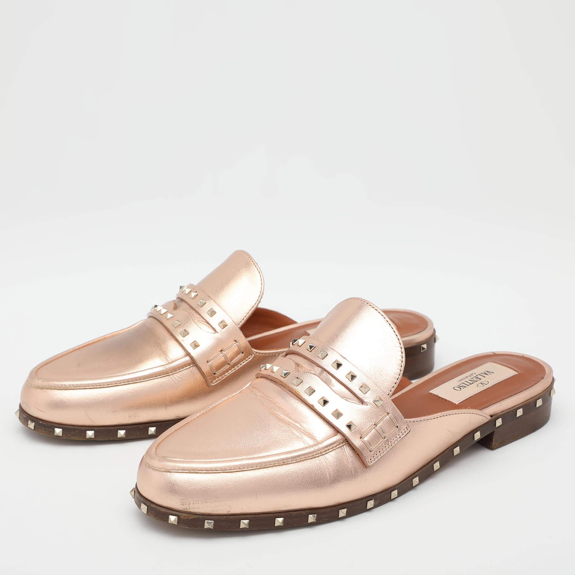 Opt for a unique style this season with these stunning Valentino flat mules. They have been expertly crafted from metallic rose gold leather and detailed with the labels signature Rockstuds on the vamps and midsoles. They are set on a low lying heel