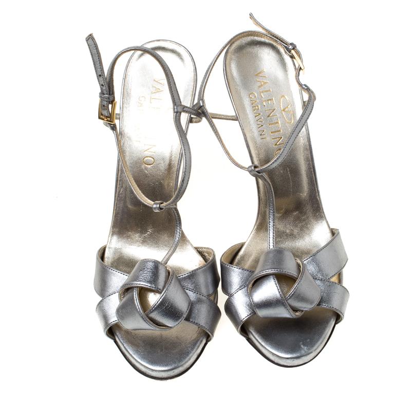 These metallic silver leather sandals by Valentino are a high-end fashion item that you need to own now. Flaunt your stylish best side with these T-strap sandals featuring buckle ankle straps, knotted uppers and 12 cm heels.

