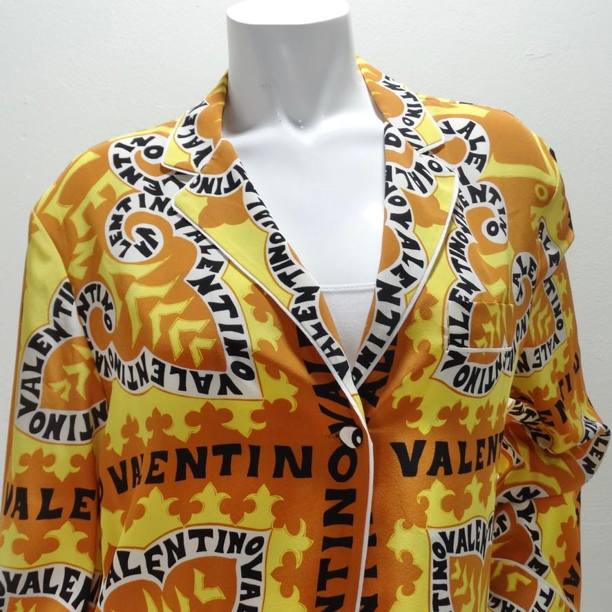 Do not miss out on this absolutely stunning Valentino button up blouse! Luxurious 100% silk fabric is adorned in the most beautiful Valentino logo graphic print in a range of warm toned and neutral hues. The graphic of this shirt draws in the eye