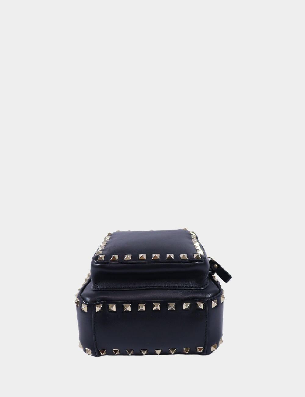 Audacieux, audacieux et résolument Valentino, ce mini-sac à dos Valentino Garavani Rockstud est réalisé en cuir noir épuré et orné des clous pyramidaux dorés emblématiques de la marque. Doté d'une silhouette compacte, d'une poche zippée à l'avant et