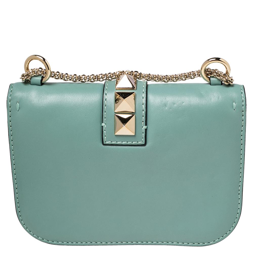 If you are looking for a bag with a blend of modern style, glamour, and class, this Valentino creation is the answer. Crafted from leather in a mint green shade, this piece comes with a slender chain strap and a flap with a push-lock to secure the