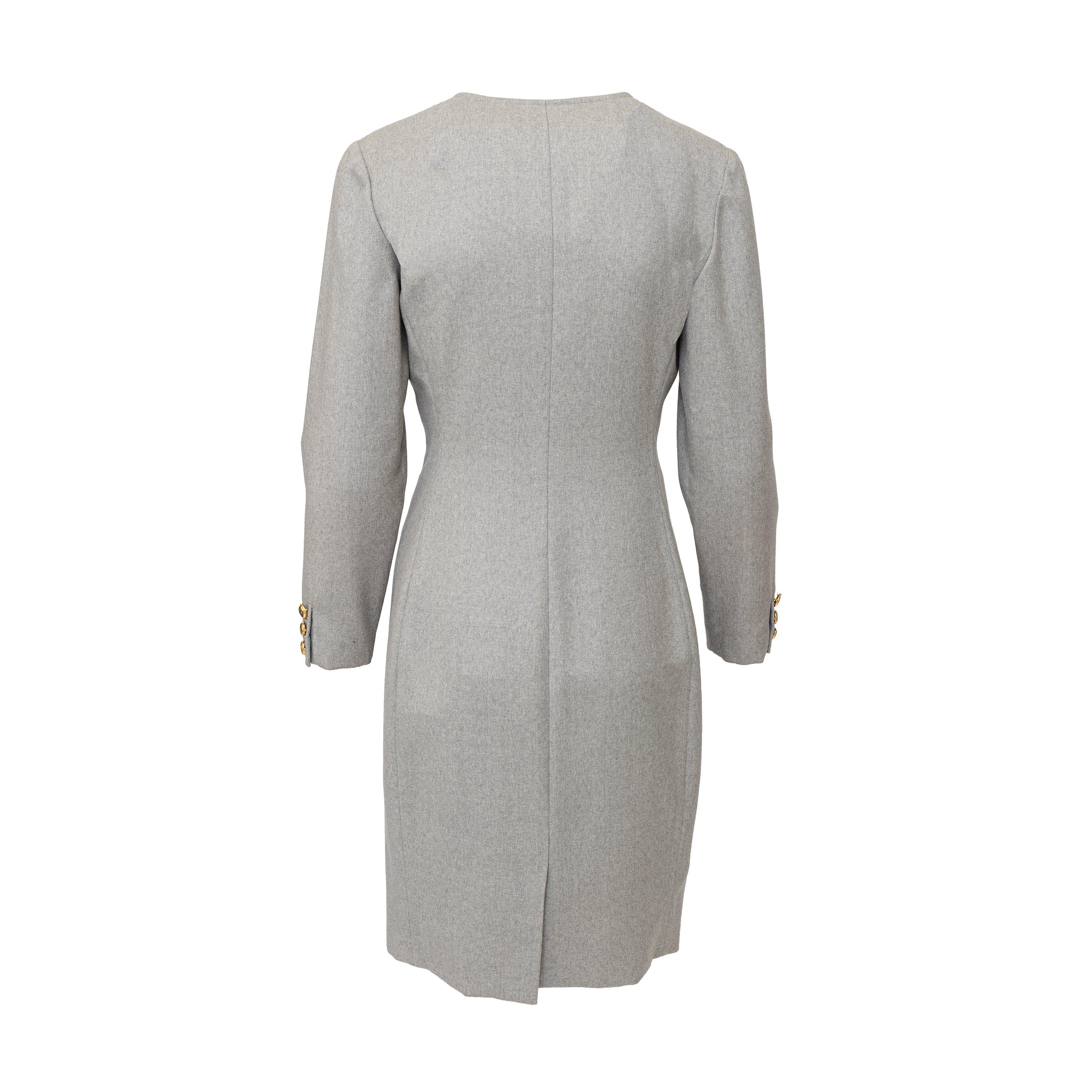 This light grey wool midi dress from the 1991 Miss V collection features a round neck, long sleeves, and decorative flap pockets. The golden turtle buttons add a touch of elegance to this 90s vintage piece. Perfect for a professional yet elegant