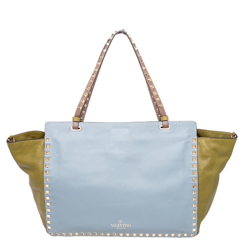 Valentino brings you this super-stylish tote that carries a design that will surely grab the attention of your onlookers. It has a fabulous multicolor exterior and the signature pyramid studs decorated on the surface, on the two top handles, and on