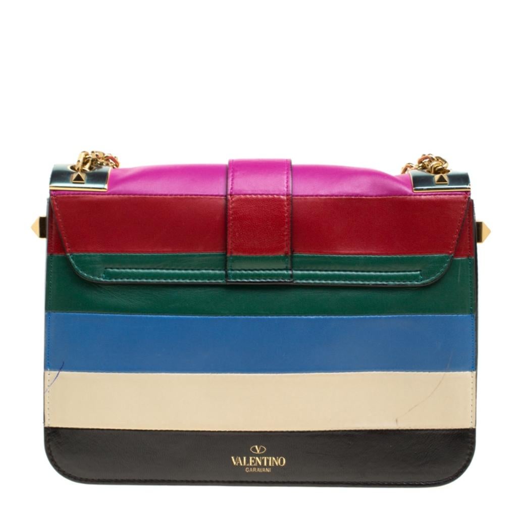 Valentino brings you this super-stylish bag that carries a design which will surely grab the attention of your onlookers. It has a fabulous leather exterior decorated with stripes in multiple colours and the signature Rockstuds detailed lock closure
