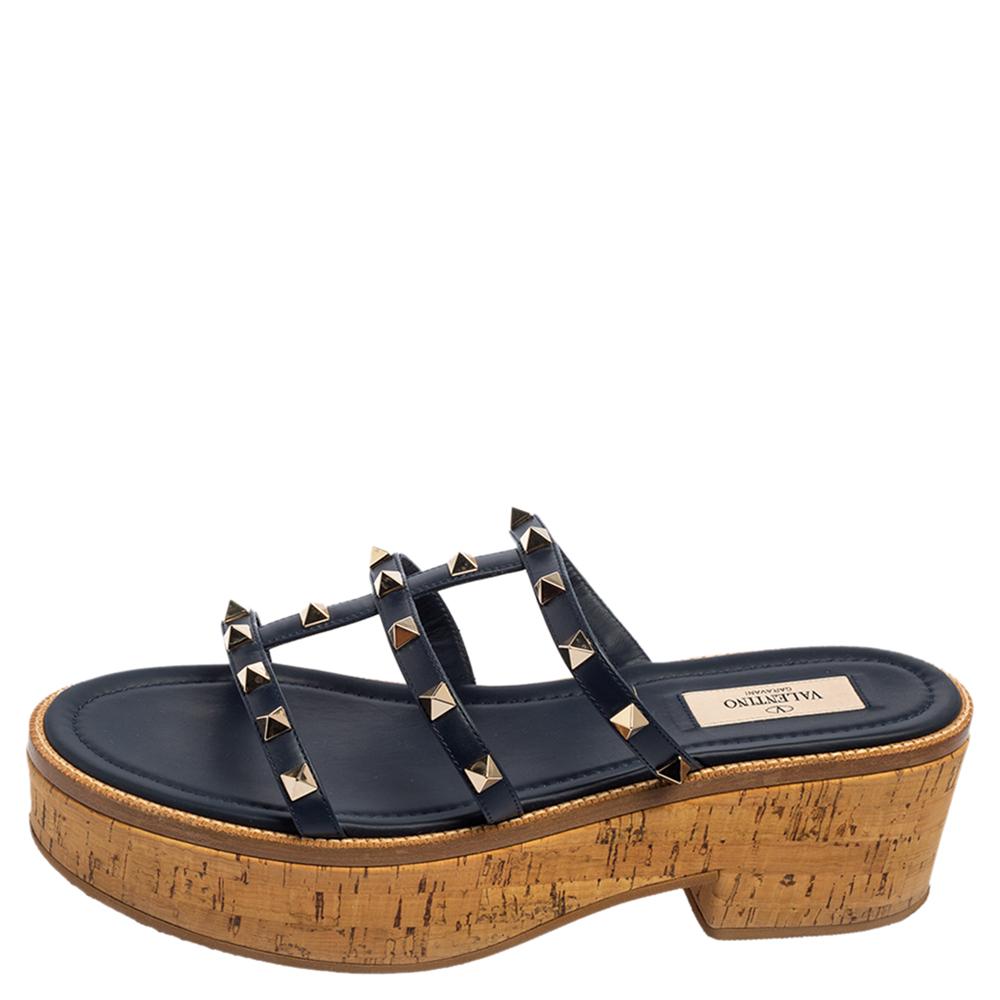 A perfect mix of elegant fashion and feminine style, these Valentino sandals come crafted from navy blue leather and detailed with the signature Rockstud accents on the vamp straps. These visually stunning sandals are complete with cork platforms