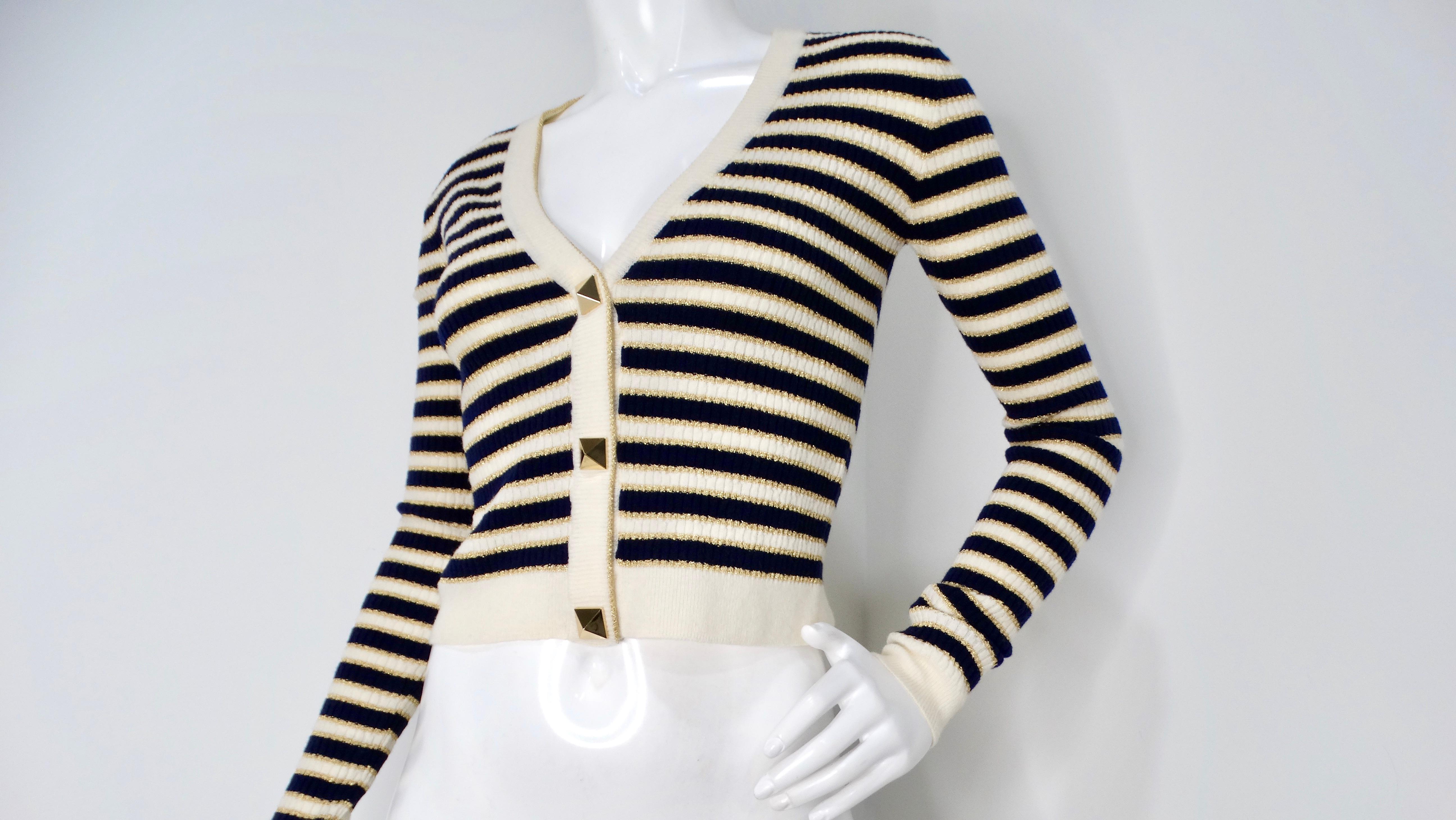 The Valentino Navy, Cream & Gold Lurex Striped Rockstud Button Cropped Cardigan is a statement piece exuding Italian luxury. The navy, cream, and gold lurex stripes create a visually striking pattern, elevated by the iconic Rockstud embellishments
