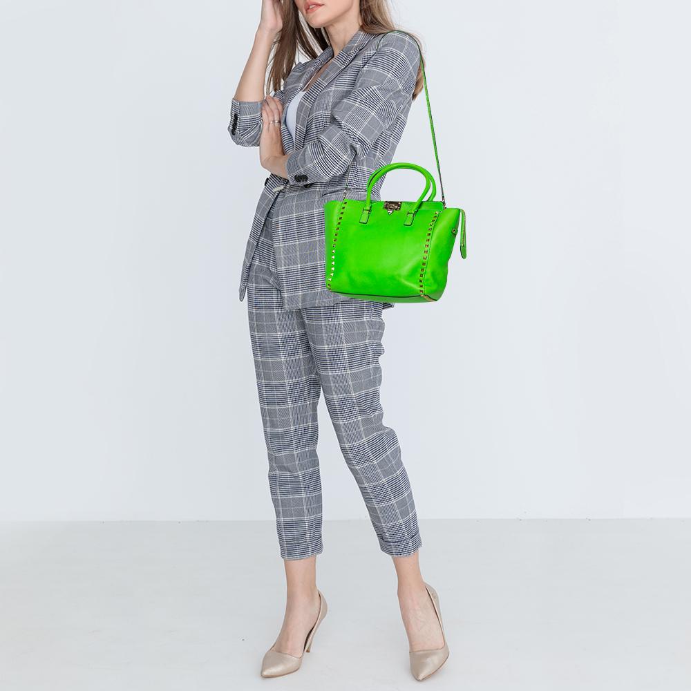 Valentino brings you this super-stylish tote cast in a design that transcends trends. It has a neon green leather exterior decorated with the signature pyramid Rockstuds. The tote is complete with a spacious canvas interior, two top handles, and a