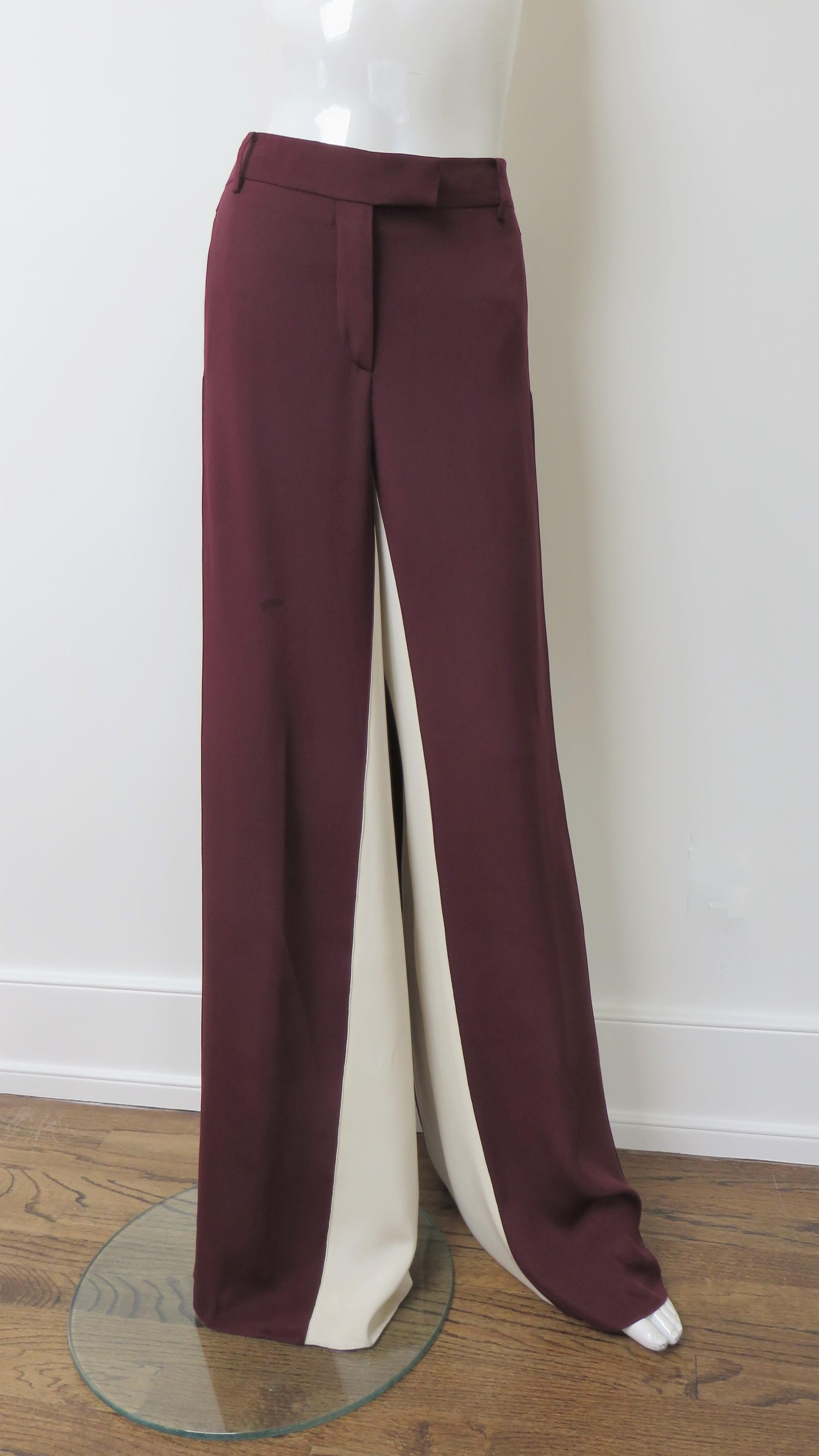 Beautiful burgundy and off white silk color block pants from Valentino. They have a waistband, fly front zipper, hip seam pockets and 2 back button welt pockets. The wide leg pants are burgundy in the front/back and off white along the outer and