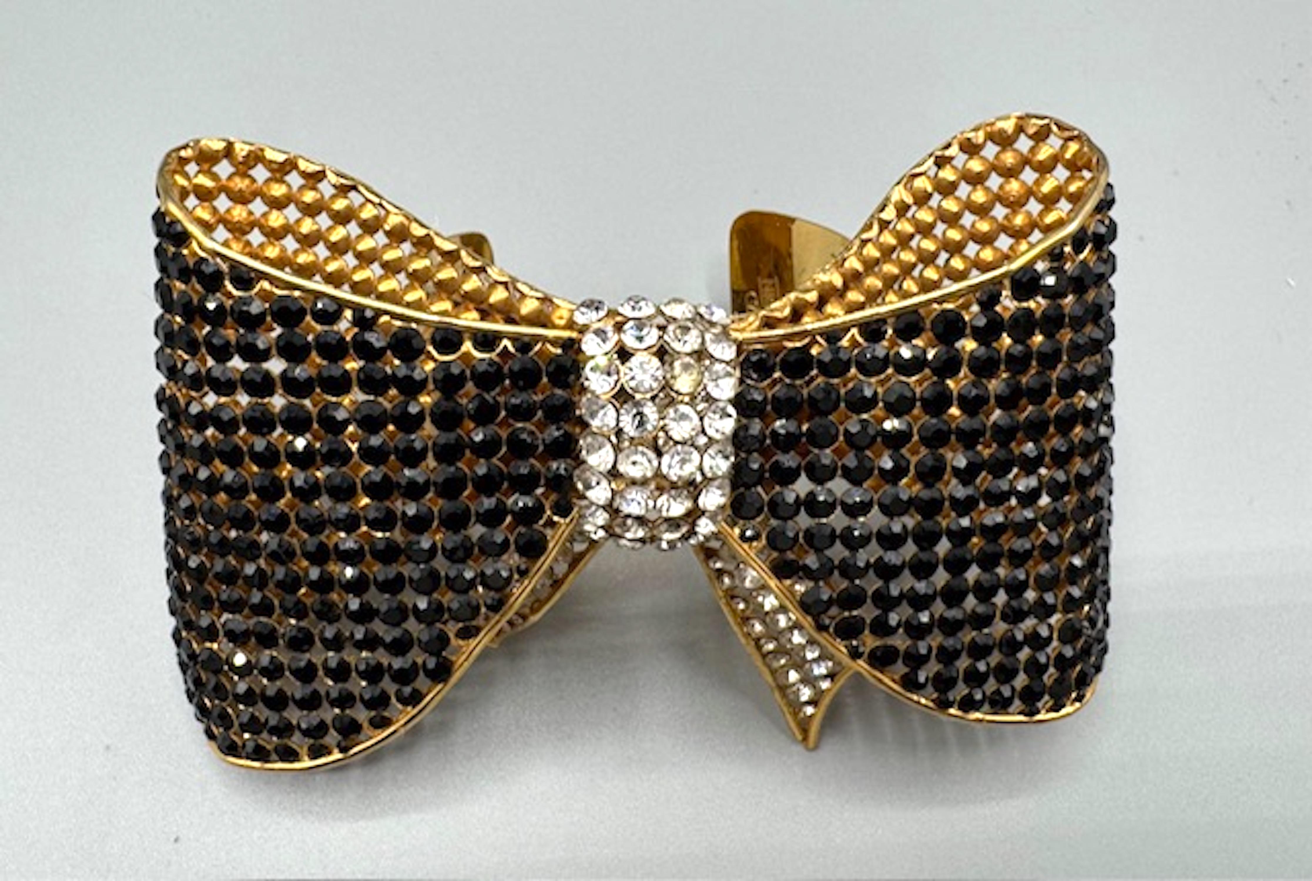 Questo bracciale con fiocco degli anni '80 è uno splendido pezzo vintage che mette in mostra l'eccezionale maestria e attenzione ai dettagli di Valentino Garavani. L'intricato design a fiocco traforato ornato di strass neri e trasparenti, unito alla