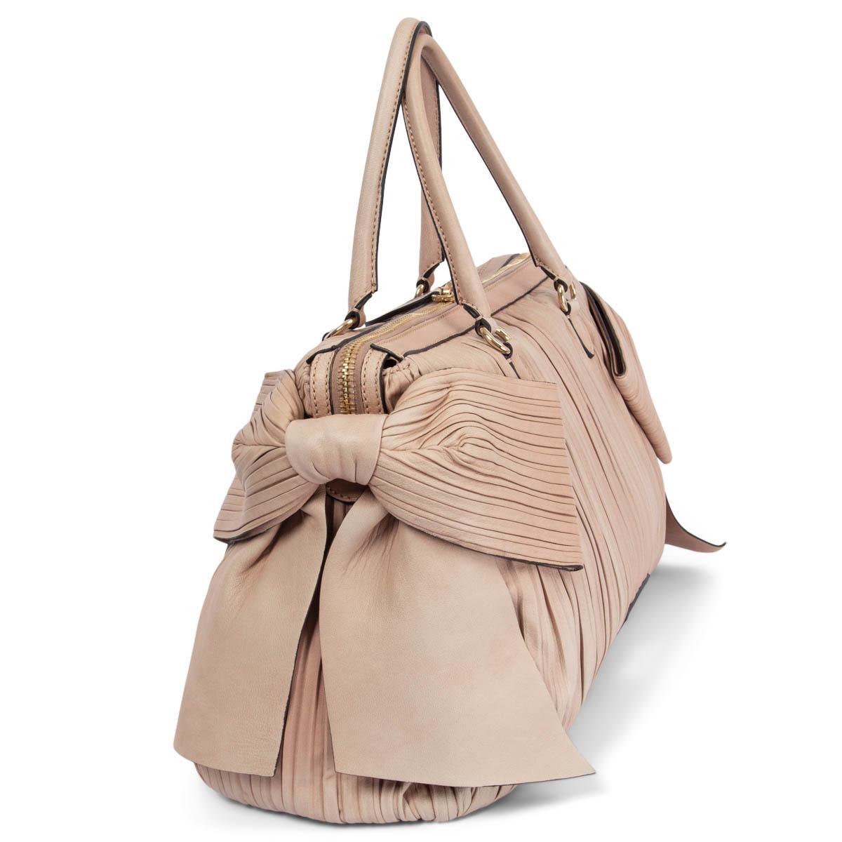 100% authentic Valentino Garavani pleated and side bow embellished handbag in nude soft calfskin. Opens with a double zipper on top and is lined in beige canvas with one zip pocket against the back and two open pockets against the front. Has been