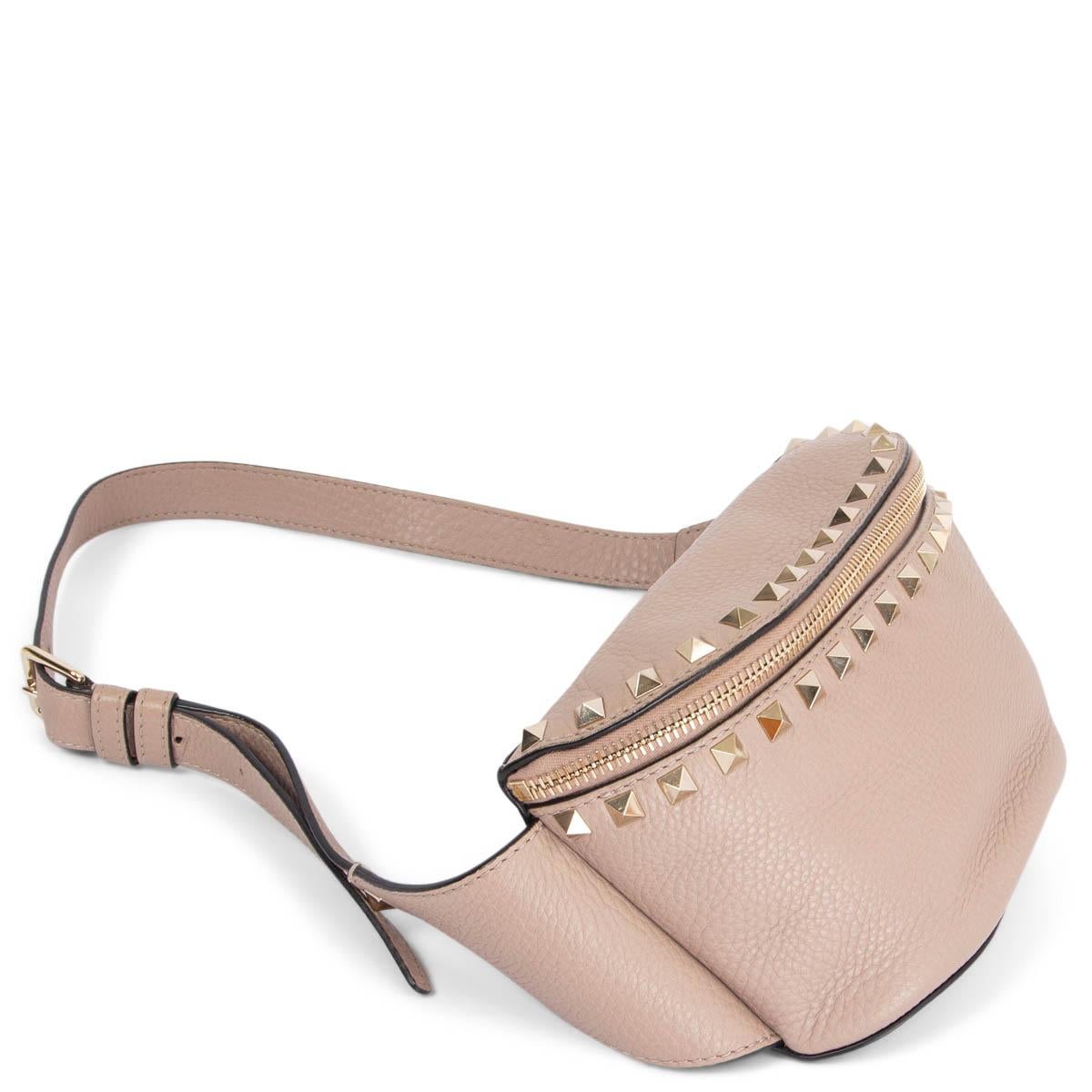 100% authentic Valentino Rockstud belt bag in grainy dusty pink leather featuring signature light gold-tone pyramid studs and a zipper pocket at the back. Opens with a zipper on top and is lined in off-white canvas with a open pocket against the