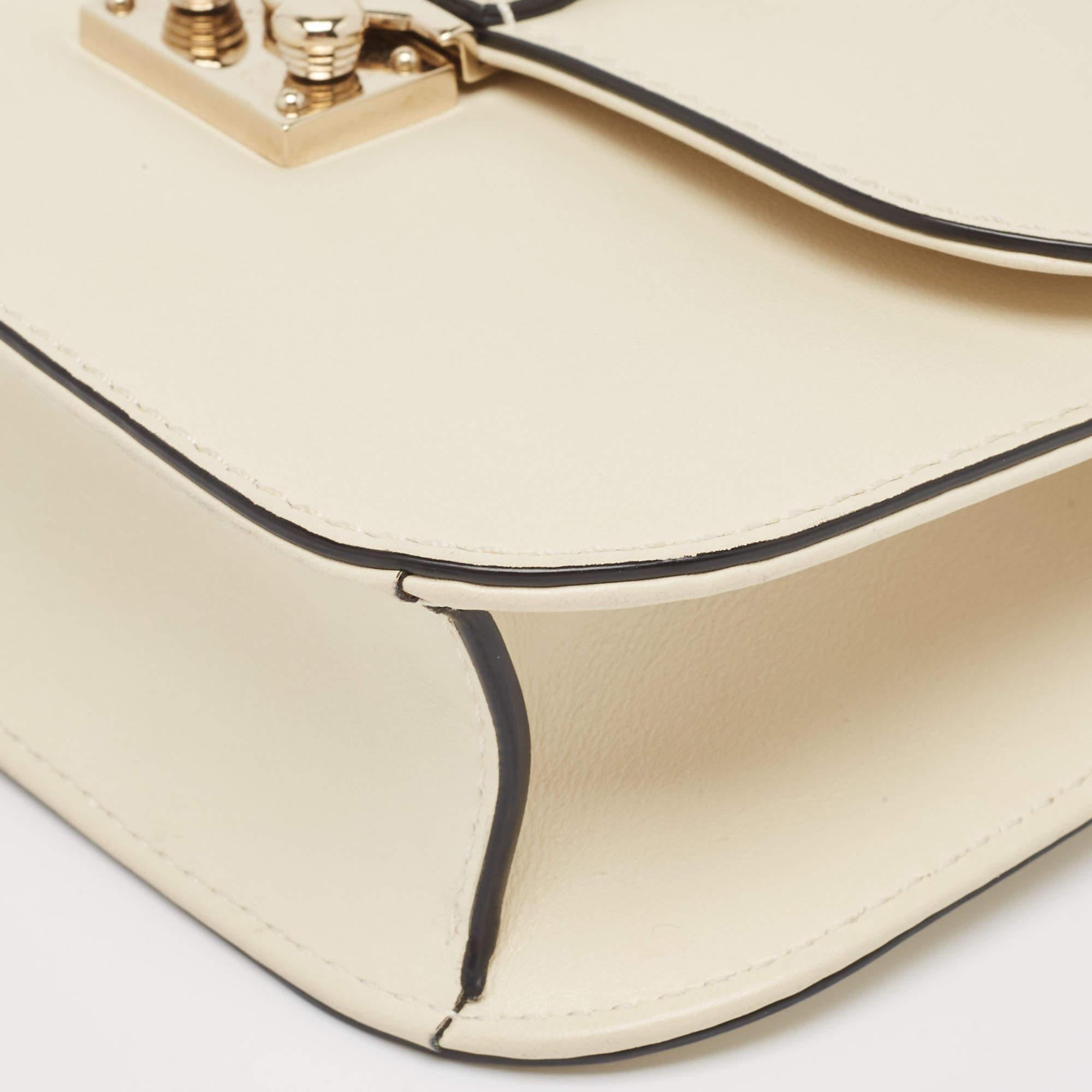 Celebrating the rich heritage of the brand, this Valentino bag is decorated with Rockstuds. It is made from leather, and it showcases a noteworthy design. Lined with fabric, it is secured by a branded lock closure on the front flap. While the chain