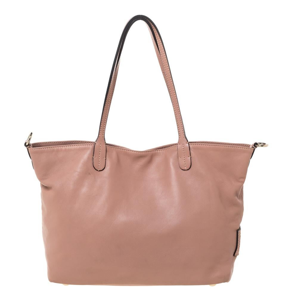 Valentino is known to bring out unique and one-of-a-kind pieces year after year and this tote is indeed one of them! It is crafted beautifully from old rose leather with flower appliques on the front and a brand label plaque on the side. It comes