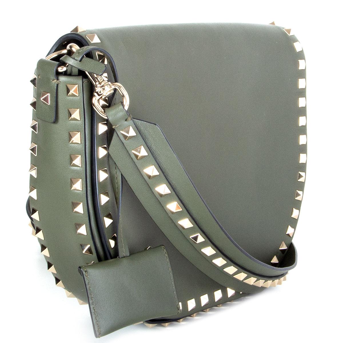 100% authentic Valentino Rockstud Saddle bag in olive green calfskin featuring signature light gold-tone pyramid studs. Comes with a slit pocket on the back and a detachable shoulder strap. Opens with a magnetic button under flap. Lined in off-white