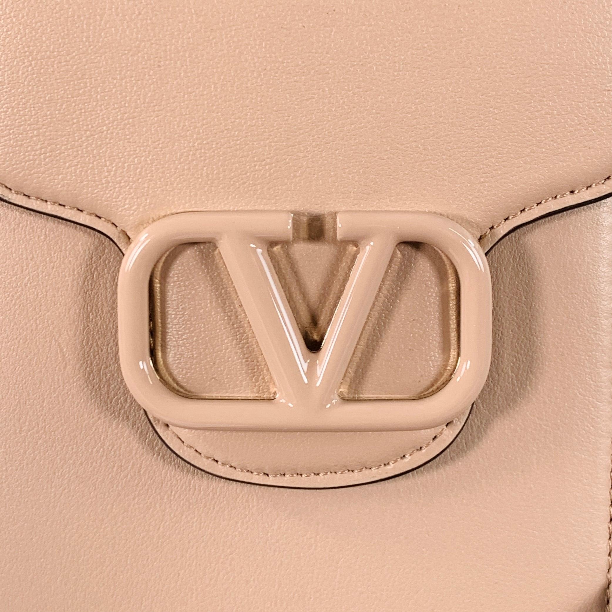 Sacoche de téléphone VALENTINO
en cuir beige avec logo en métal ton sur ton, bandoulière amovible et fermeture aimantée. Livré avec boîte et sac à poussière.New with Box. 

Mesures : 
  Longueur : 3,25 pouces Largeur : 1,25 pouces Hauteur : 7 pouces