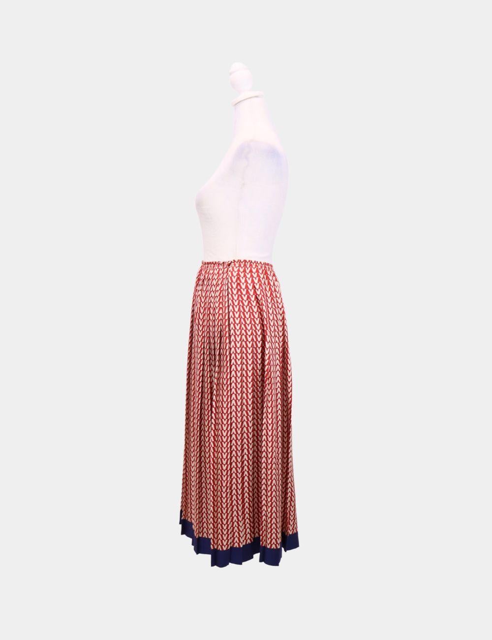 Effortlessly elegant and unmistakably Valentino, this red and navy pleated midi skirt is a timeless statement piece. Featuring a refined geometric print and finely pleated construction, it flows beautifully with every step. The contrast navy hem