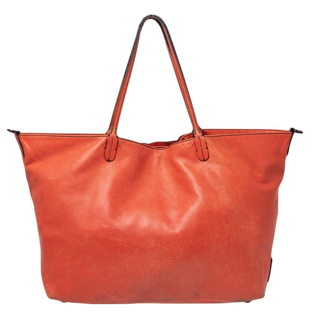 A chic, casual tote for everyday excursions crafted in leather with a beautiful rose petal design on the front, this tote is by Valentino. It comes with two handles, a shoulder strap, and a large storage compartment. It is best suited for casual and