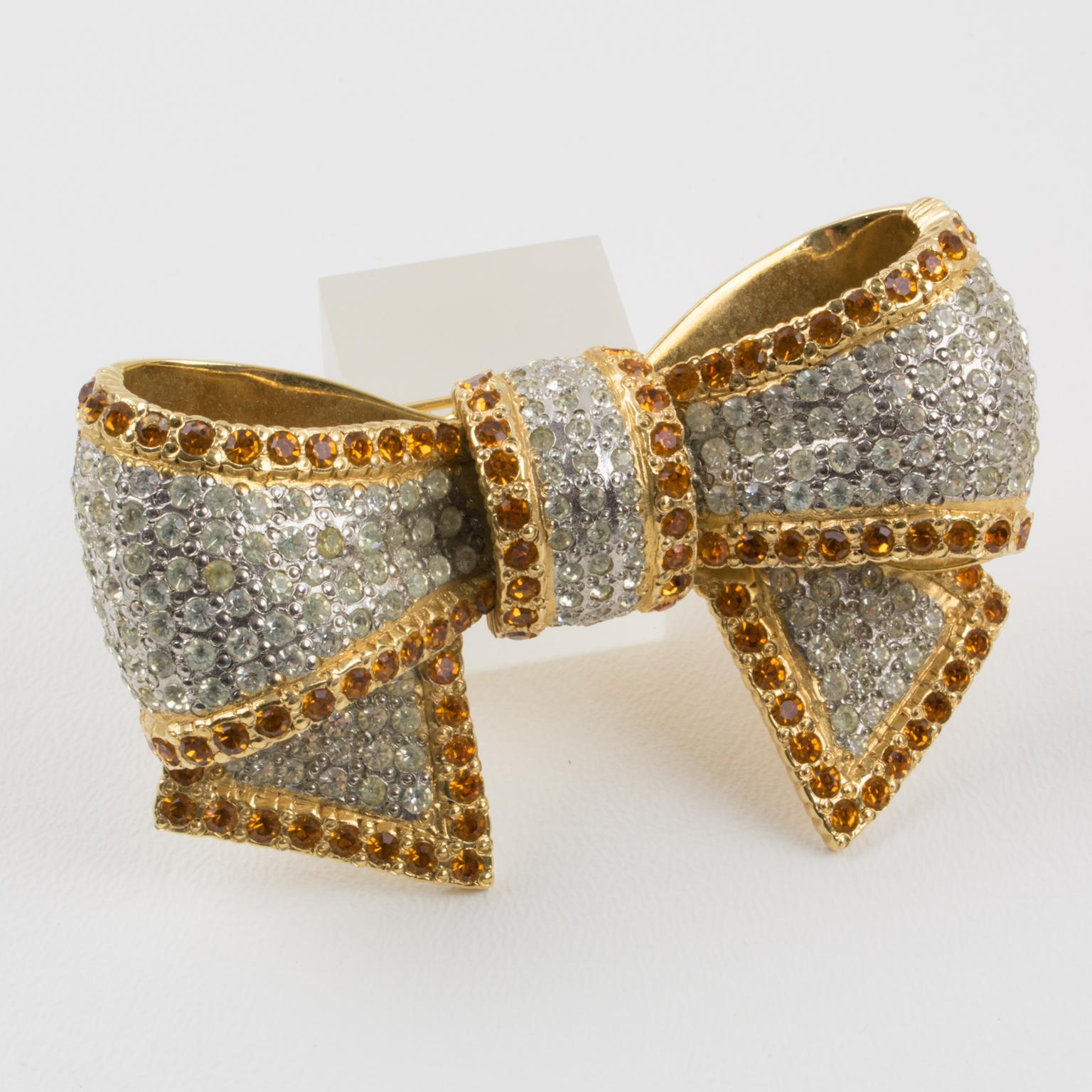 Exquisite Valentino Garavani couture pin brooch. Huge dimensional gilt metal bowtie-shape all paved with tiny crystal rhinestones in assorted colors of clear and topaz. Security closing clasp. Valentino hallmark underside.
Measurements: 3 in. wide