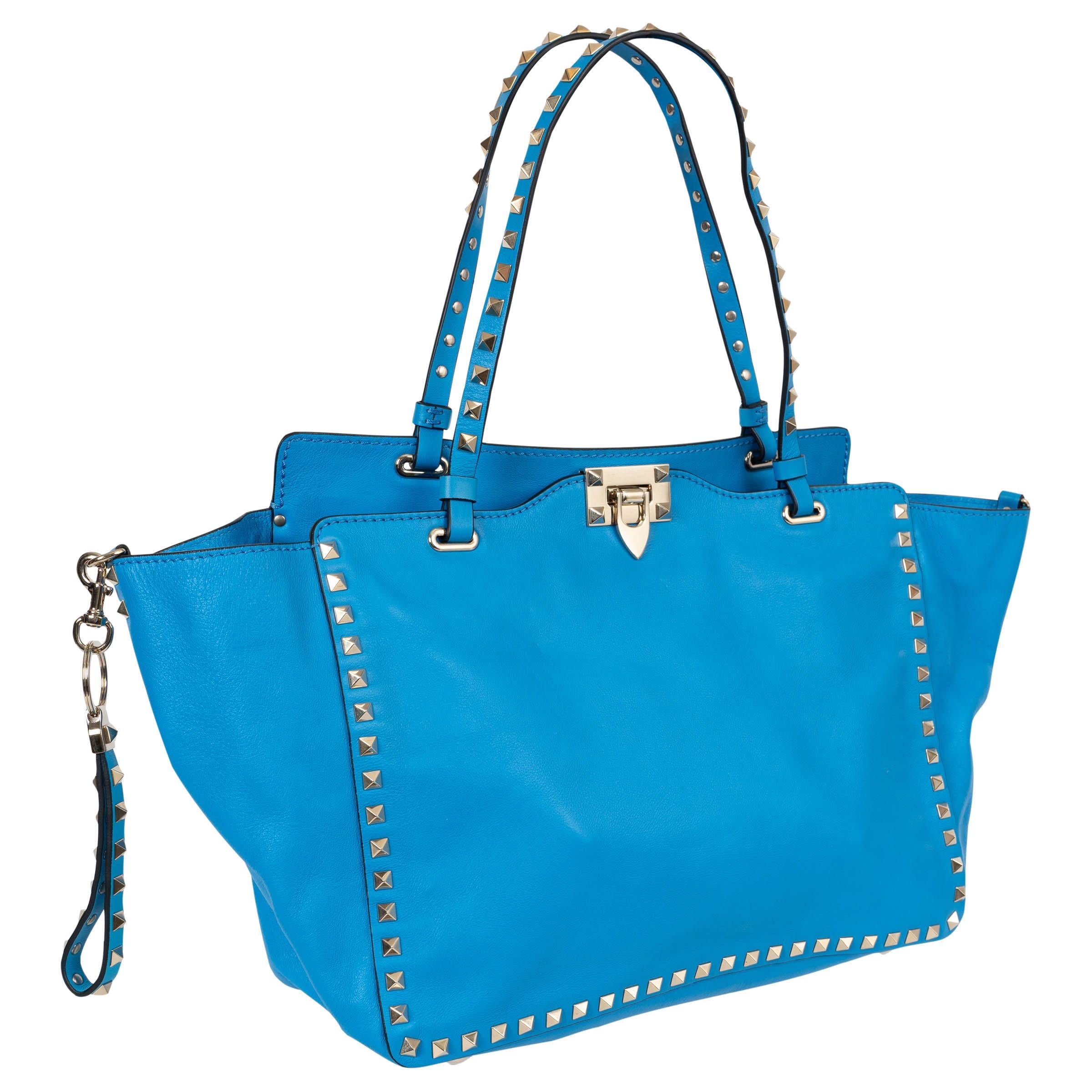 Diese 100% authentische Valentino Medium Rockstud Trapeze Umhängetasche aus Parrot (hellblauem) Kalbsleder ist ein gewagtes und doch zeitloses Statement. Sie ist mit den kultigen platinfarbenen Rocknieten aus hellgoldfarbenem Metall verziert und