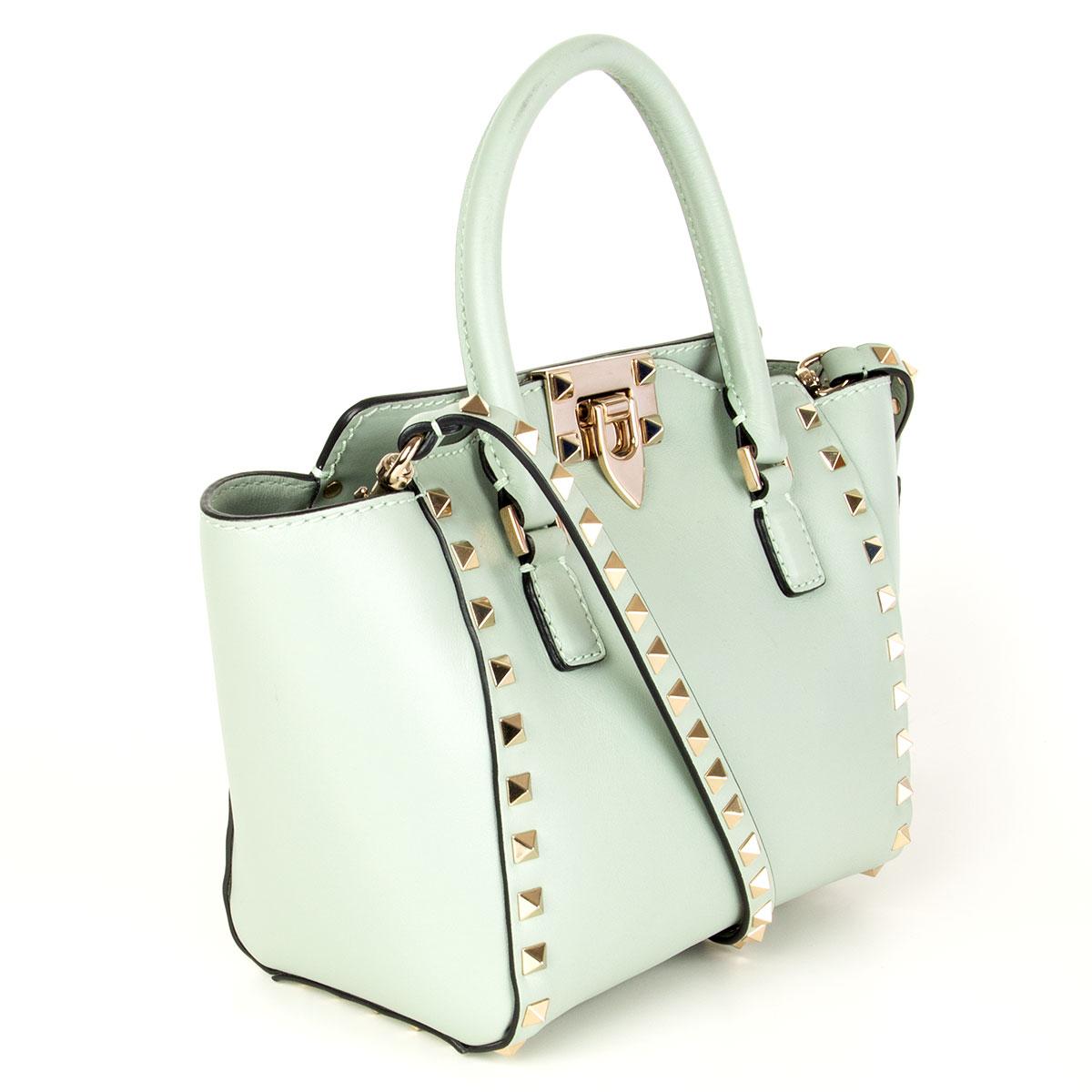  Valentino 'Rockstud Mini Double Handle' in pastel sage green calfskin featuring light gold-tone platinum-finish stud details. Flip lock closure and zip closure. Detachable studded shoulder strap. Lined in beige canvas with one open pocket against