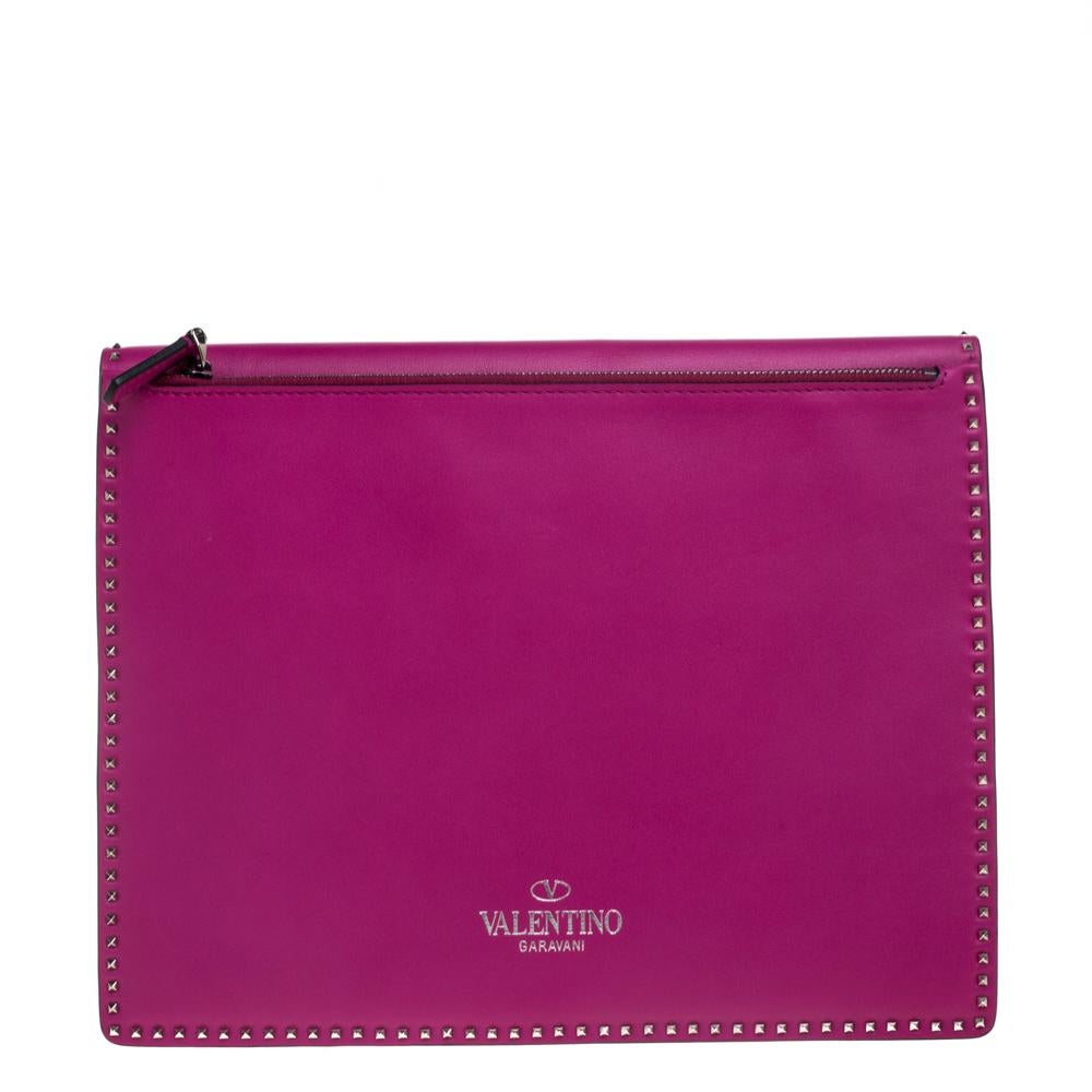 This flat clutch by Valentino is crafted from leather and features a flap with a turn lock. Its pink hue provides an elegant allure and the fine detailing of signature studs adds a distinct touch. The interior is leather-lined and will safely hold