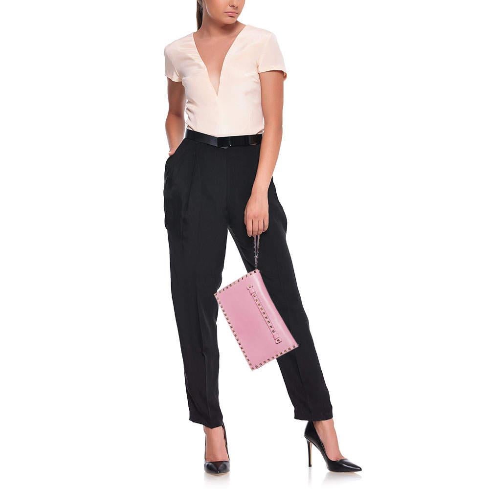Have all eyes on you when you flaunt this Rockstud clutch by Valentino. Crafted from pink leather it comes with the iconic Rockstud detailing on the exterior. The leather lined interior houses compartments and a zip pocket. Complete with a wristlet