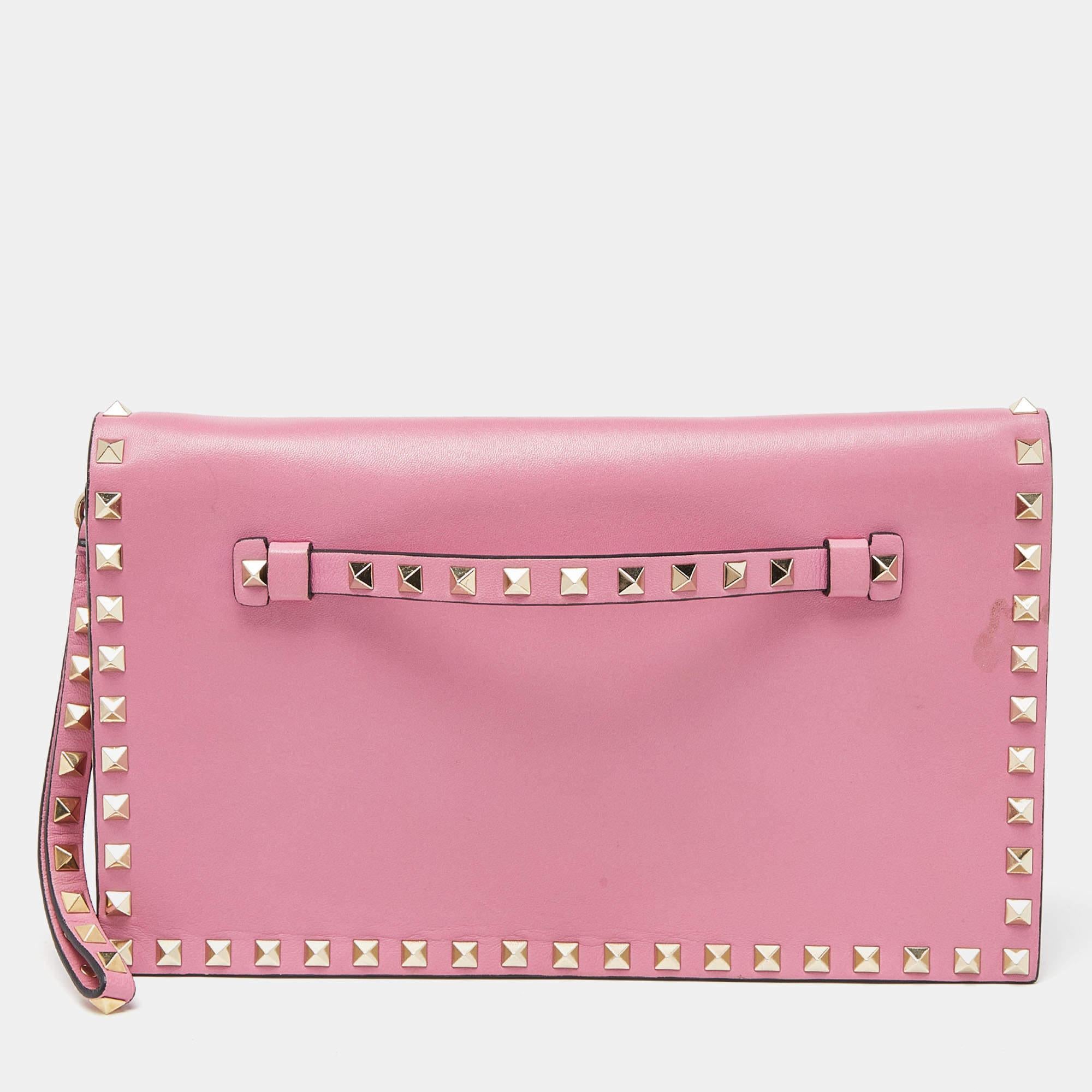Have all eyes on you when you flaunt this Rockstud clutch by Valentino. Crafted from pink leather, it comes with the iconic Rockstud detailing on the exterior. The leather-lined interior houses compartments and a zip pocket. Complete with a