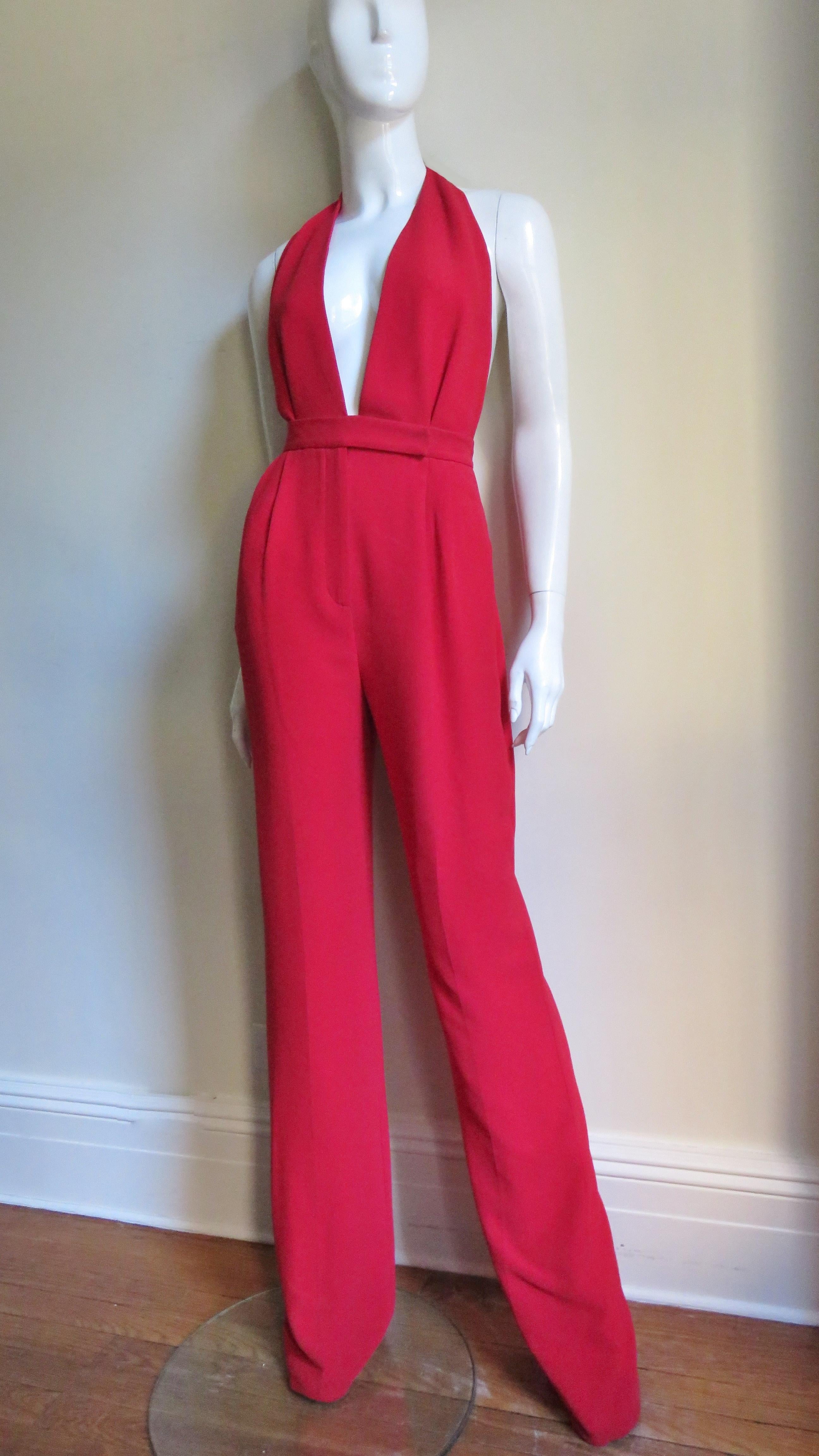 An incredible red silk jumpsuit from Valentino.  It is halter style with a plunging neckline to the waist.  The bodice has 2 front tucks as do the pants at the waistband that joins them.  The legs are full.  The jumpsuit has side seam hip and back
