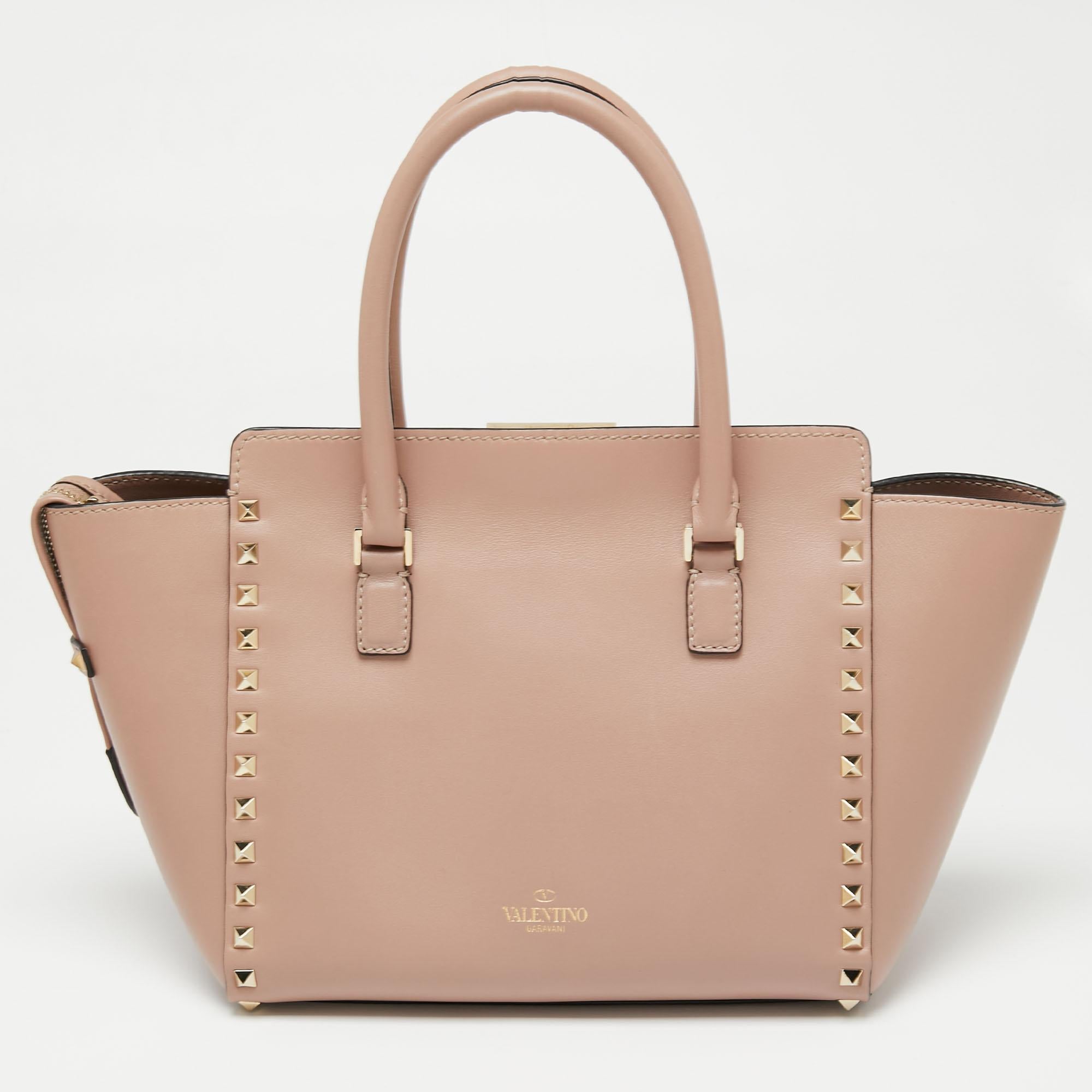 Luxury Italian fashion house Valentino is famed for its classic designs infused with its own signature modern edge and Rockstud details as showcased by this trapeze tote. Crafted from leather, it features top handles and a detachable shoulder strap
